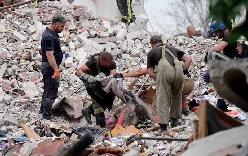 Firefighters and members of a rescue team clear debris after a building was partially destroyed following shelling, in Chasiv Yar, eastern Ukraine, on July 10, 2022. - A Russian missile struck an apartment building in Chasiv Yar, in eastern Ukraine on July 10, 2022. (Photo by MIGUEL MEDINA / AFP)