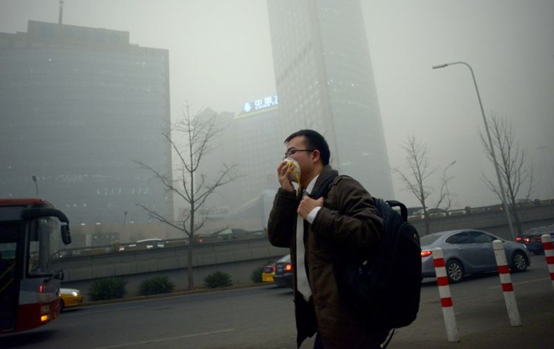 A man wearing a mask walks along a road in heavy pollution in Beijing on December 1, 2015. Beijing ordered hundreds of factories to shut and allowed children to skip school as choking smog reached over 25 times safe levels on December 1, casting a cloud over China's participation in Paris climate talks.          AFP PHOTO / WANG ZHAO / AFP / WANG ZHAO