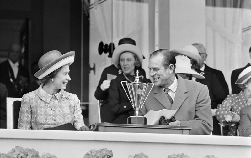 (FILES) In this file photograph taken on May 18, 1972, Britain's Queen Elizabeth II (L) and her husband Prince Philip Duke of Edinburgh speak as they attend a horse race at Longchamp Racecourse, on the outskirts of Paris during a five-day official visit to France. - French President Emmanuel Macron paid tribute to Prince Philip on April 10, 2021, following his death on April 9, at the age of 99 and sent his condolences to the queen. Philip "lived an exemplary life defined by bravery, a sense of duty and commitment to youth and the environment", he said on Twitter. Macron later recalled the prince's closeness to France and his many stays on French soil, from childhood to as recently as 2014, on the 70th anniversary of the D-Day landings. Citing the Duke of Edinburgh's participation in World War II and medals including the Legion d'honneur, Macron said "he knew the price paid by our two countries, allies and brothers in the fight for freedom." (Photo by STAFF / AFP)