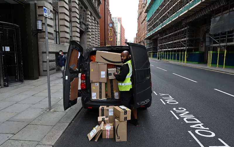 A delivery driver unloads Amazon-branded boxes in Manchester, northwest England as the country battles a surge in coronavirus cases on October 19, 2020 (Photo by Paul ELLIS / AFP)