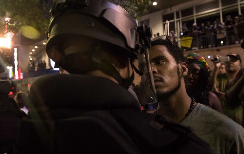 A protester stares at riot police during a demonstration against police brutality in Charlotte, North Carolina, on September 21, 2016, following the shooting of Keith Lamont Scott the previous day.
A protester in Charlotte, North Carolina was fatally shot by a civilian during a second night of unrest after the police killed a black man, officials said. / AFP PHOTO / NICHOLAS KAMM