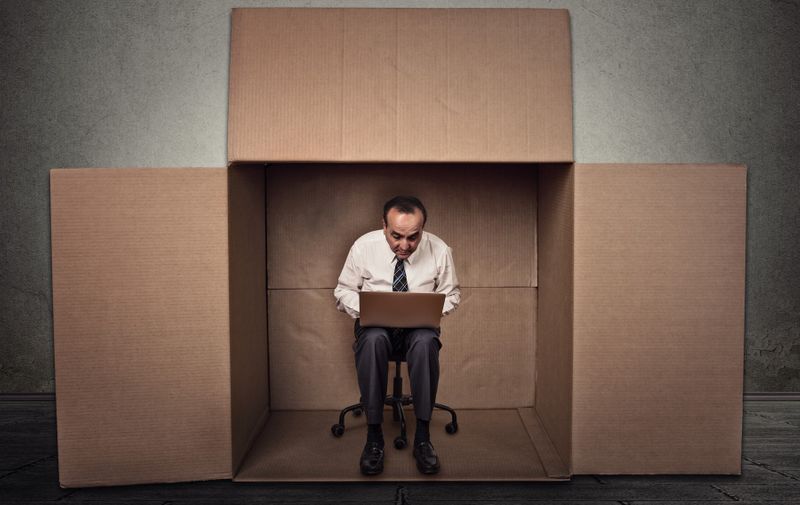 Limitations poor communication of corporate life. Portrait corporate middle aged man working on laptop sitting on chair inside carton box in empty office room,Image: 405939395, License: Royalty-free, Restrictions: , Model Release: yes, Credit line: Profimedia