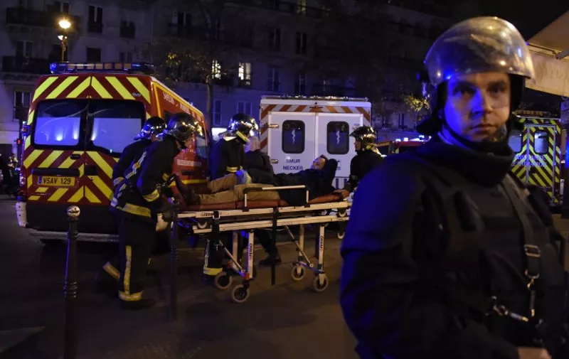 Rescuers workers evacuate a man on a stretcher near the Bataclan concert hall in central Paris, on November 13, 2015. A number of people were killed and others injured in a series of gun attacks across Paris, as well as explosions outside the national stadium where France was hosting Germany. AFP PHOTO / DOMINIQUE FAGET / AFP / DOMINIQUE FAGET