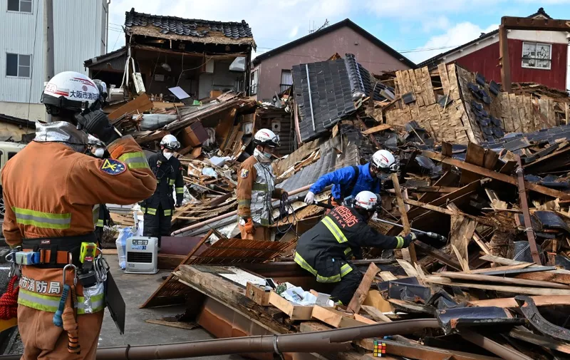 Firefighters search for people in the rubble of a collapsed house in the city of Wajima, Ishikawa prefecture on January 4, 2024, after a major 7.5 magnitude earthquake struck the Noto region in Ishikawa prefecture on New Year's Day. More than 50 people were reported missing January 4 as Japanese rescuers battled to reach hundreds still cut off from help three days after a devastating earthquake left at least 78 dead. (Photo by Kazuhiro NOGI / AFP)