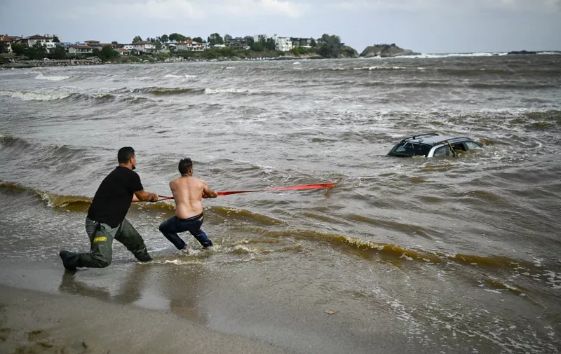 People try to pull out a car submerged in the sea at Arapia camping site near Tsarevo along the Bulgarian Black sea coast, on September 6, 2023. The death toll from torrential rains and flooding on Bulgaria's Black Sea coast has climbed to three, police said on September 6. Heavy rain and thunderstorms since late September 4 caused rivers to overflow, damaging bridges and causing more than 100 seaside holidaymakers and locals to be evacuated to safer grounds. (Photo by Nikolay DOYCHINOV / AFP)