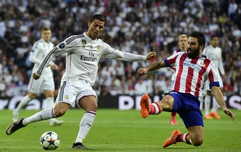 Real Madrid&#8217;s Portuguese forward Cristiano Ronaldo (L) vies with Atletico Madrid&#8217;s Turkish midfielder Arda Turan during the UEFA Champions League quarter-finals second leg football match Real Madrid CF vs Club Atletico de Madrid at the Santiago Bernabeu stadium in Madrid on April 22, 2015. AFP PHOTO /
