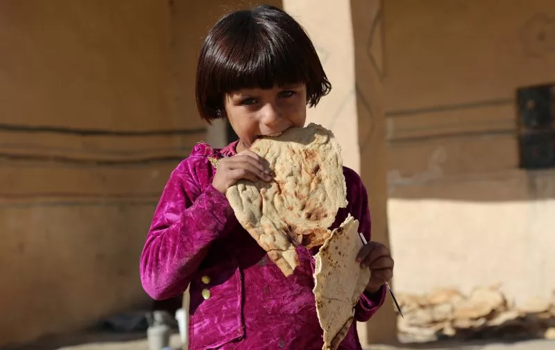 TO GO WITH AFP STORY
A Syrian girl eats bread in the Al-Shallal suburb of the northeastern town of Al-Hol in Syria's Hasakeh province, bordering with Iraq, on November 19, 2015, after Syrian Democratic Forces (SDF) re-took control of the area from IS jihadists. The town was once a key way-station for IS between the territory it holds between Iraq and Syria, and its capture was a strategic victory for the new  SDF coalition, an alliance of the powerful Kurdish People's Protection Units (YPG) and Arab and Christian armed opposition groups.  AFP PHOTO / DELIL SOULEIMAN / AFP / DELIL SOULEIMAN