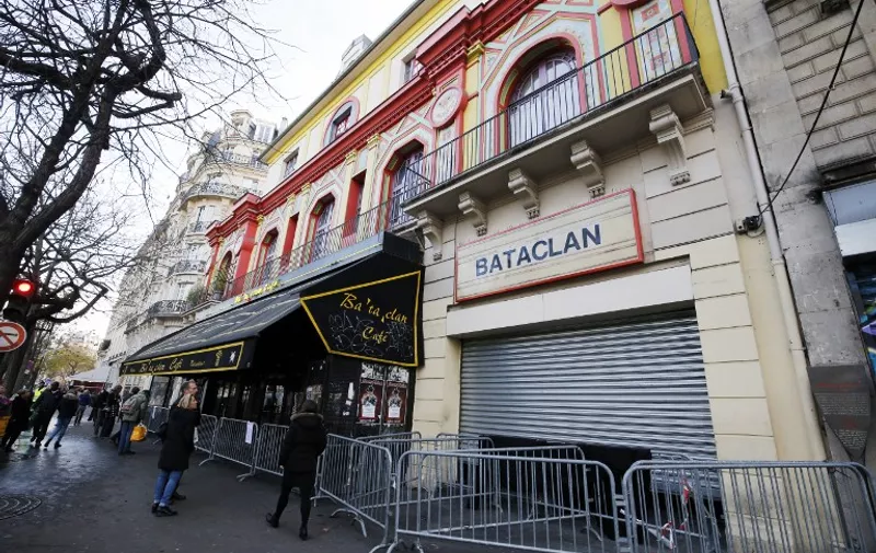 People walk past the Bataclan concert hall in Paris on December 22, 2015, after the sidewalk in front of the venue was once again made accessable to pedestrians.
A coordinated series of gun and bomb attacks at several sites in Paris on November 13, including the Bataclan concert hall, left 130 dead. / AFP / FRANCOIS GUILLOT