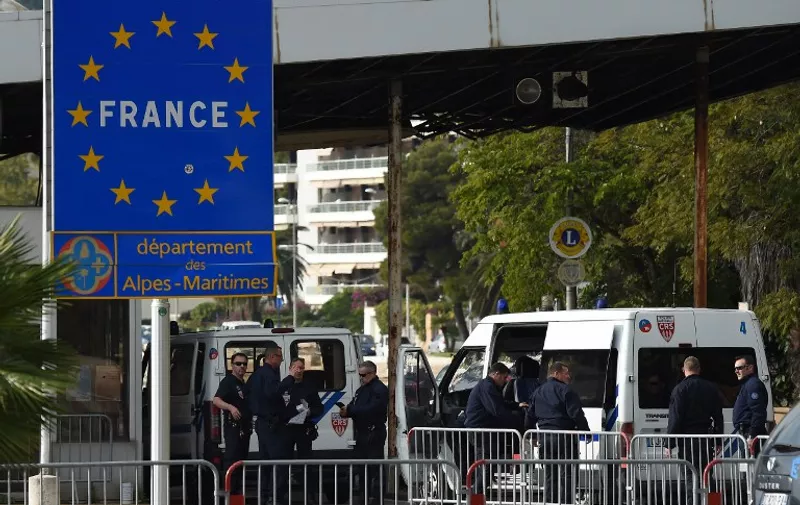 French police officers supervise the toll at the French-Italian border in Menton on November 13, 2015. 30,000 police officers, including 4 000 border police (PAF : Police aux frontières), are mobilized from November 13 until December 13 to help secure French borders at 285 crossing points as part of the COP21 environmental summit to be held in Paris. Thousands of customs officers will also take position regularly on former checkpoints. AFP PHOTO / ANNE-CHRISTINE POUJOULAT