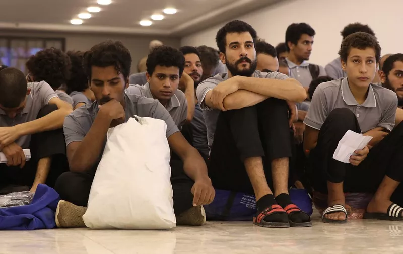 Migrants await processing during a deportation operation by the Ministry of Interior in the Tripoli-based government, in the Libyan capital on November 6, 2023. (Photo by Mahmud Turkia / AFP)