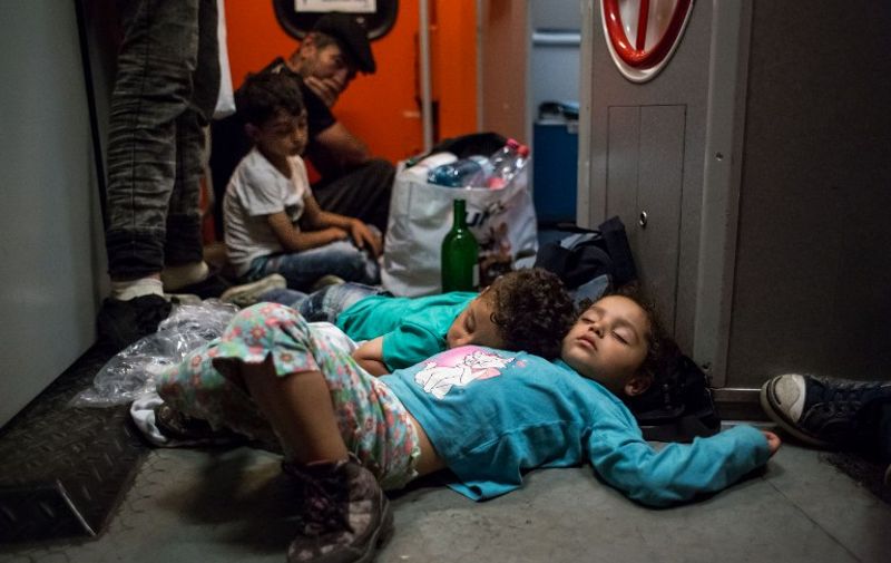 Migrant children sleep on the floor on the train from Budapest to Munich at the Austrian - Hungarian border in Hegyeshalom on August 31, 2015. Austrian security forces stopped two trains with several hundreds migrants on board near the border with Hungary on Monday, a police spokesman said, just hours after authorities in Budapest let them leave despite many not having the right visas to travel in the EU. AFP PHOTO/ VLADIMIR SIMICEK