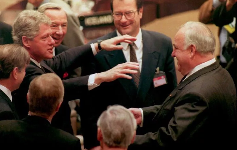 (FILES) In this file photo taken on January 10, 1994, then US President Bill Clinton (L) greets then German Chancellor Helmut Kohl (R) as they meet prior to the opening of the NATO summmit in Brussels, Belgium; in the background are then US Secretary of State Warren Christopher (2ndL) and then German Foreign Minister Klaus Kinkel (C). (Photo by MIKE SARGENT / AFP)