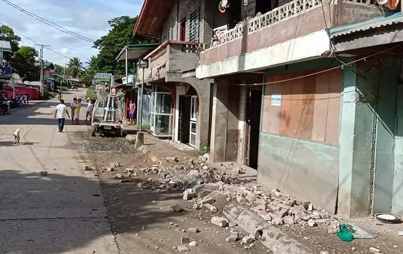 This handout photo received on August 18, 2020 from the Facebook page of Jake Gabilan shows residents walking past debris on the ground after a 6.7-magnitude earthquake hit near the town of Cataingan in the central Philippine province of Masbate province. - The strong earthquake shook the central Philippines on August 18, sending residents fleeing their homes and damaging buildings and roads, with at least one person reported killed. (Photo by Handout / Courtesy of Jake Gabilan / AFP) / -----EDITORS NOTE --- RESTRICTED TO EDITORIAL USE - MANDATORY CREDIT "AFP PHOTO / Courtesy of Jake Gabilan" - NO MARKETING - NO ADVERTISING CAMPAIGNS - DISTRIBUTED AS A SERVICE TO CLIENTS  - NO ARCHIVES