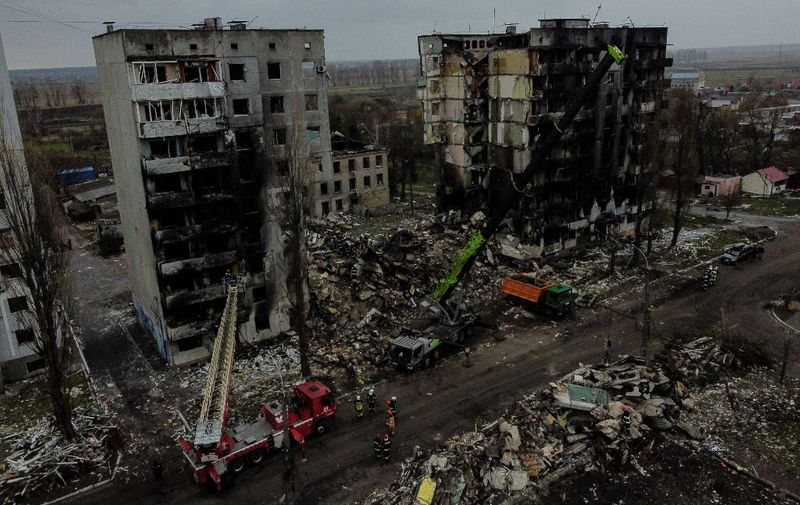 An aerial view taken on April 8, 2022 shows diggers working in the rubble of collapsed buildings in the town of Borodianka, northwest of Kyiv. (Photo by RONALDO SCHEMIDT / AFP)