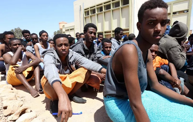 Migrants from sub-Saharan Africa sit at a center for illegal migrants in the al-Karem district of the Libyan eastern port city of Misrata on April 15, 2015, after their boat was intercepted by the Libyan coast guard. AFP PHOTO / MAHMUD TURKIA