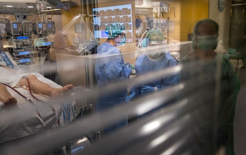 Health workers attend to a COVID-19 patient at the intensive care unit of the Vall d'Hebron hospital in Barcelona on April 1, 2020. - Spain's death toll surged over 9,000 as infections passed the 100,000 mark, but the rate of new cases continued to slow, suggesting the epidemic may be peaking, health chiefs said. (Photo by RICARDO GARCIA VILANOVA / AFP)