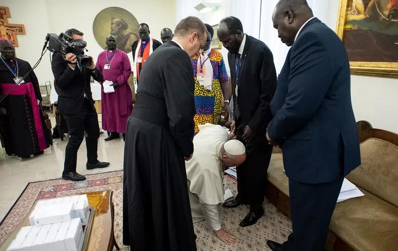 In this photo taken and released on April 11, 2019 by the Vatican Press Office, Vatican Media, Pope Francis (Bottom) kneels to kiss the feet of South Sudan's President Salva Kiir Mayardit (C) and South Sudan opposition leader Riek Machar (R) at the Pope's Santa Marta residence in the Vatican. - Pope Francis on April 11 knelt and kissed the feet of leaders of South Sudan at the end of a two-day retreat to help them solidify a peace agreement. (Photo by Handout / VATICAN MEDIA / AFP) / RESTRICTED TO EDITORIAL USE - MANDATORY CREDIT "AFP PHOTO / VATICAN MEDIA" - NO MARKETING NO ADVERTISING CAMPAIGNS - DISTRIBUTED AS A SERVICE TO CLIENTS ---