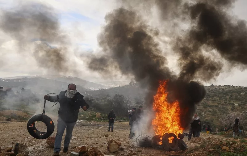 Palestinian protesters burn tyres during a demonstration in the village of Baita, south of Nablus in the occupied West Bank, against the establishment of Israeli outposts on their lands, on February 3, 2023. (Photo by Jaafar ASHTIYEH / AFP)