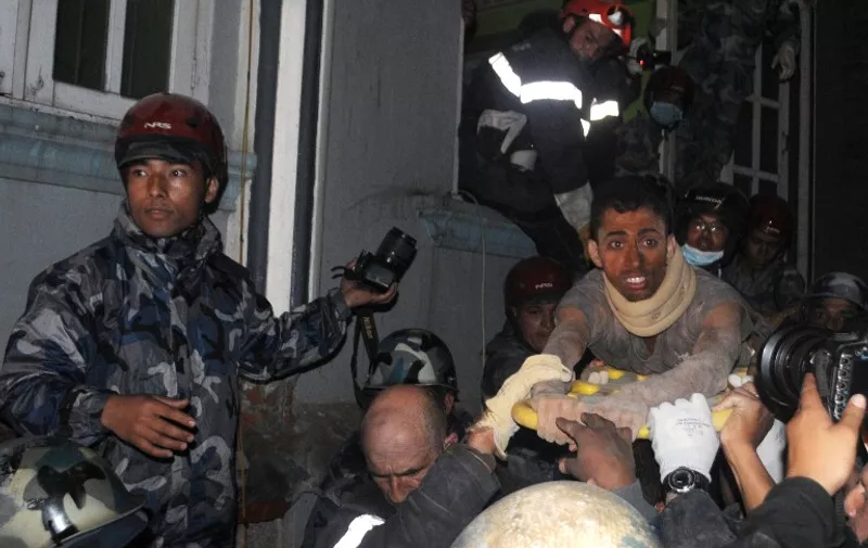 Nepalese and French rescue teams take out from a damaged building Nepalese Rishi Khanal, 27, an injured survivor, to carry him to hospital, 82 hours after the earthquake, on April 28, 2015 in Kathmandu. Hundreds of thousands of Nepalis spent another night in the open on April 27 after a massive quake which killed more than 4,000, as officials warned the final toll could rise sharply once rescuers reach cut-off areas. AFP PHOTO / BIKASH KARKI