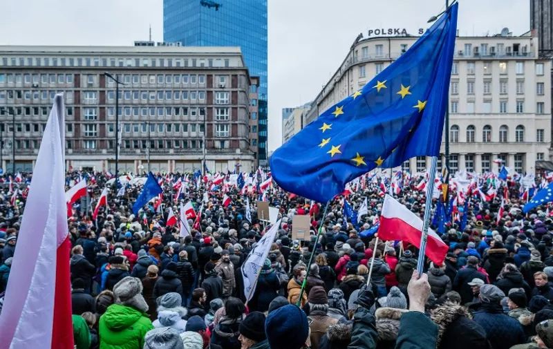 People wave European and Polish flags as they take part in a protest against a new media law in the center of Warsaw on January 9, 2016. 
Since returning to power in October, Poland's Law and Justice (PiS) party has taken several controversial step which critics have denounced as undermining the independence of both the media and the judiciary. / AFP / WOJTEK RADWANSKI