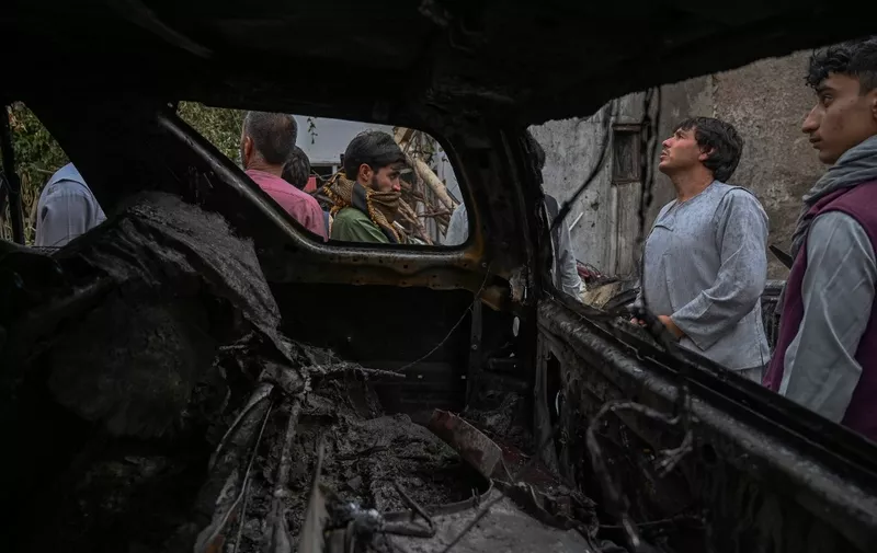 Afghan residents and family members of the victims gather next to a damaged vehicle inside a house, day after a US drone airstrike in Kabul on August 30, 2021. (Photo by WAKIL KOHSAR / AFP)
