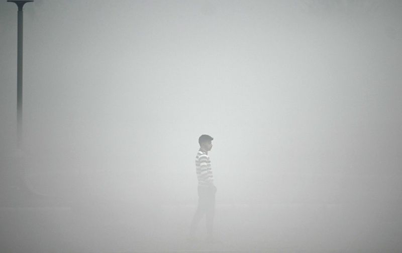 A pedestrian walks along the roadside amid heavy smoggy conditions in New Delhi on November 13, 2023. Delhi regularly ranks among the most polluted major cities on the planet, with a melange of factory and vehicle emissions exacerbated by seasonal agricultural fires. (Photo by Money SHARMA / AFP)