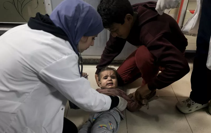 EDITORS NOTE: Graphic content / A medic checks a Palestinian child from the Baraka family brought into Nasser Hospital in Khan Yunis, following Israeli air strikes that hit their building in the southern Gaza Strip city on November 13, 2023. Israel is facing intense international pressure to minimise civilian suffering amid a massive air and ground operation that Hamas authorities say has already killed more than 11,000 people, including thousands of children. The military campaign came after Hamas fighters broke through the militarised border with Israel on October 7, killing around 1,200 people, mostly civilians, and taking about 240 people hostage, according to the most recent Israeli figures. (Photo by Mahmud HAMS / AFP)