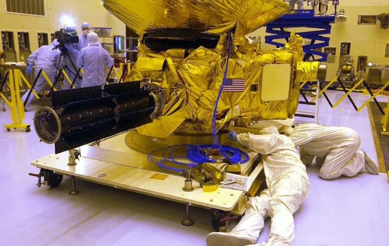 Engineers from Johns Hopkins University check out NASA's New Horizons spacecraft 04 November 2005 in the Payload Hazardous Servicing Facility at Kennedy Space Center, Florida in preparation for its mid-January 2006 launch aboard an Atlas V rocket. The New Horizons will be the first mission to the planet Pluto and the Kuiper Belt, the journey taking about nine years.  Pluto was discovered in 1930 at a distance of some 6.4 billion kilometers (three billion miles) from the sun in the heart of the Kuiper Belt -- a zone beyond Neptune 4.5-7.5 billion kilometers (2.8-4.6 billion miles) from the sun, which is estimated to include more than 35,000 objects of more than 100 kilomters (65 miles) in diameter: the remnants of the sun's accretion ring of matter from which all the planets were formed.  AFP PHOTO/Bruce WEAVER