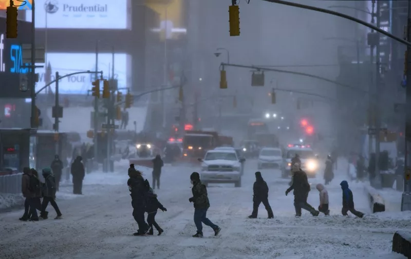 Pedestrians cross a street during a winter storm in New York on January 29, 2022. - A powerful winter storm packing heavy snow and high winds pummeled the US East Coast Saturday, forcing the cancellation of thousands of flights as severe weather alerts were sounded across a region of around 70 million people. (Photo by Ed JONES / AFP)