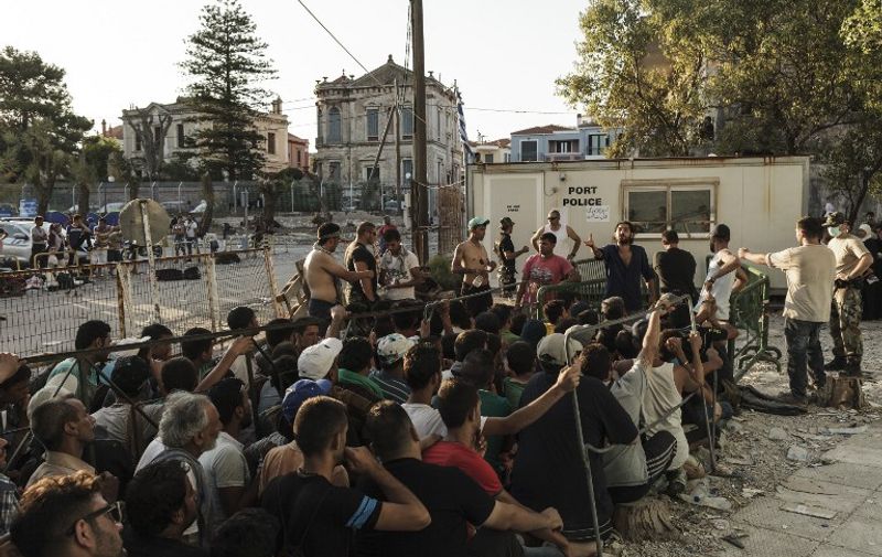 Syrian migrants waiting in line to register with the police authorities at Mytilini port on the island of Lebos, on August 17, 2015. Migrants escaping Syria, Afghanistan, Africa and elsewhere are taking advantage of the calm summer conditions to make daily attempts to cross the Aegean between the Bodrum peninsula and Kos, one of the narrowest waterways between Turkey and the European Union.  AFP PHOTO/ ACHILLEAS ZAVALLIS