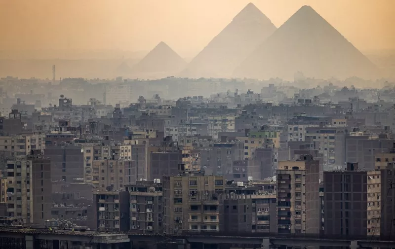 This picture taken on November 1, 2022 shows a view of the skyline of Giza, the twin-city of Egypt's capital, with the (L to R) Great Pyramid of Khufu, the Pyramd of Khafre, and the Pyramid of Menkaure seen in the background, and the new third line of the Cairo Metro in the foreground. (Photo by Amir MAKAR / AFP)