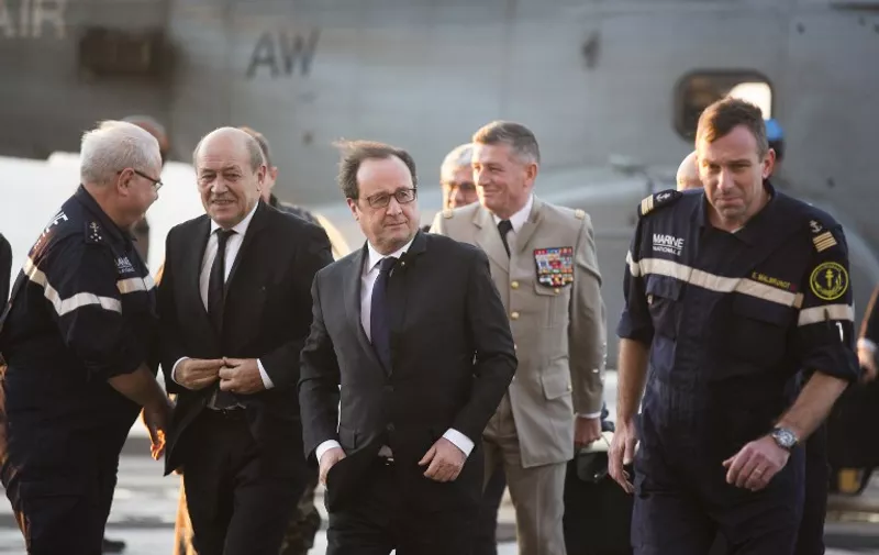 French President Francois Hollande (C) and French Defence Minister Jean-Yves Le Drian (2nd L) arrives on France's Charles de Gaulle aircraft carrier on December 4, 2015 off the coast of Syria.  
Hollande is expected to give a speech to the crew of the carrier which is off the coast of Syria, three weeks after he declared "war" on the jihadists after attacks on Paris in which 130 were killed. / AFP / POOL / Philippe de Poulpiquet