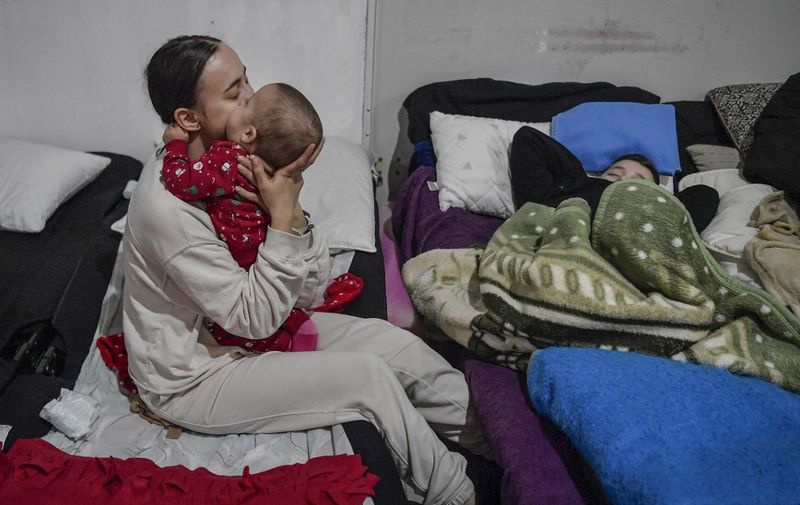 A young mother comforts her infant in a temporary shelter for Ukrainian refugees, located near the Polish-Ukrainian border in a former shopping center in Przemysl, Poland, on March 8, 2022. - More than two million people have fled Ukraine since Russia launched its full-scale invasion less than two weeks ago, the United Nations said on March 8, 2022. Poland alone has received nearly half of all those fleeing Ukraine, with figures dated March 8, 2022 showing that 1,2 million had crossed into the country in the past 13 days. (Photo by Louisa GOULIAMAKI / AFP)