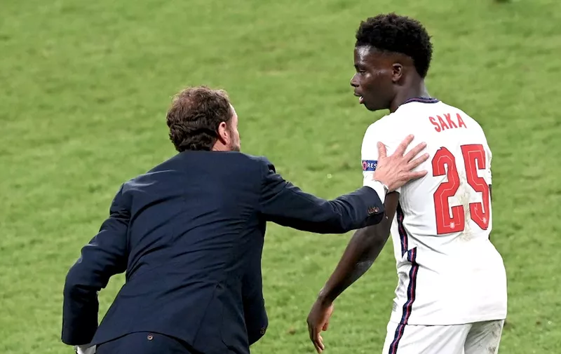 England's coach Gareth Southgate (L) speaks with England's midfielder Bukayo Saka during the UEFA EURO 2020 final football match between Italy and England at the Wembley Stadium in London on July 11, 2021. (Photo by FACUNDO ARRIZABALAGA / POOL / AFP)