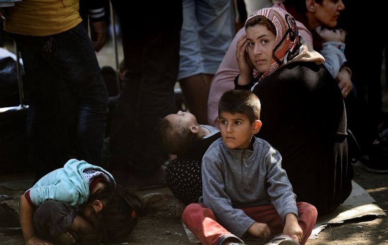 Syrian refugees and migrants wait with children at a registration camp in Presevo after their arrival in Serbia on August 30, 2015. The EU is grappling with an unprecedented influx of people fleeing war, repression and poverty in what the bloc has described as its worst refugee crisis in 50 years. AFP PHOTO / ARIS MESSINIS