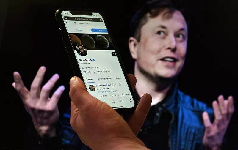 (FILES) In this file photo illustration, a phone screen displays the Twitter account of Elon Musk with a photo of him shown in the background, on April 14, 2022, in Washington, DC. - Twitter on Tuesday sued Elon Musk for breaching the $44 billion contract he signed to buy the tech firm, calling his exit strategy "a model of hypocrisy," court documents showed.
The suit filed in the US state of Delaware urges the court to order the billionaire to complete his deal to buy Twitter, arguing that no financial damages could repair the damage he has caused. (Photo by Olivier DOULIERY / AFP)