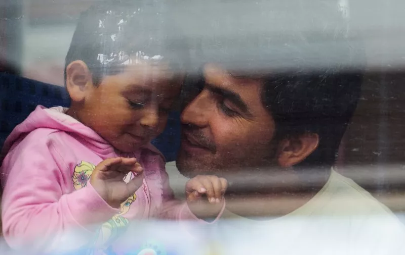 A refugee father and child at the central staion in Munich, Germany, 5 September 2015. Several refugees who arrived on a train from Salzburg were directly transfered to a waiting city train. PHOTO: NICOLAS ARMER/DPA
