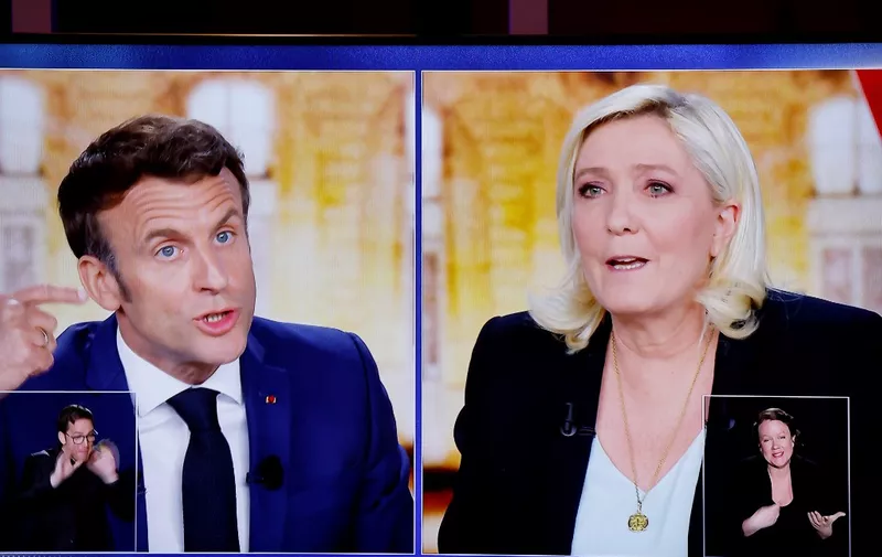 A picture shows a TV screen  displaying a live televised between French President and La Republique en Marche (LREM) party candidate for re-election Emmanuel Macron (L) and French far-right party Rassemblement National (RN) presidential candidate Marine Le Pen (R), broadcasted on French TV channels TF1 and France 2, in Saint-Denis, north of Paris, ahead of the second round of France's presidential election. - French voters head to the polls for a run-off vote between Macron and Le Pen on April 24, 2022. (Photo by Ludovic MARIN / AFP)
