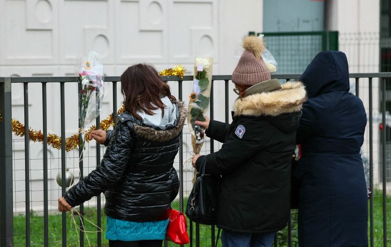 People lay flowers just in front of the ground floor flat where the bodies of a woman and her four children where discovered, in Meaux, eastern Paris, on December 26, 2023. French police arrested, the father, suspected of murdering his wife and their four children aged nine months, four, seven and 10 years old, opening an enquiry into their "premeditated murder", in Meaux, eastern Paris, on December 26, 2023. (Photo by ALAIN JOCARD / AFP)