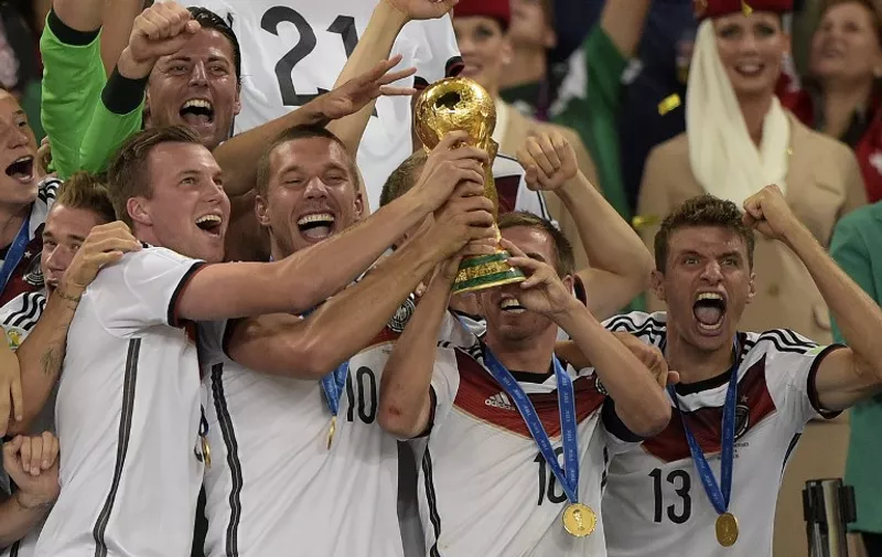 (L/R): Germany's forward Lukas Podolski , Germany's defender and captain Philipp Lahm and Germany's forward Thomas Mueller hold The World Cup as they celebrate victory in the final football match between Germany and Argentina for the FIFA World Cup at The Maracana Stadium in Rio de Janeiro on July 13, 2014. AFP PHOTO / JUAN MABROMATA