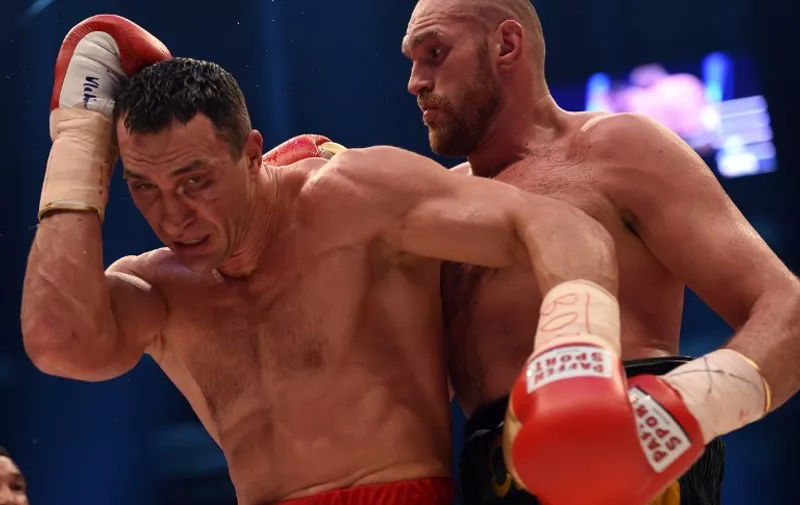 (FILES) This picture taken on November 28, 2015 shows World heavyweight boxing champion Wladimir Klitschko (L) of Ukraine defending against Britain's Tyson Fury during their  WBA, IBF, WBO and IBO title bout in Duesseldorf, western Germany. Former world heavyweight champion Wladimir Klitschko said December 2, 2015 he will take up the contractual option of a rematch against Tyson Fury in an attempt to win back his belts.  AFP PHOTO / PATRIK STOLLARZ / AFP / PATRIK STOLLARZ