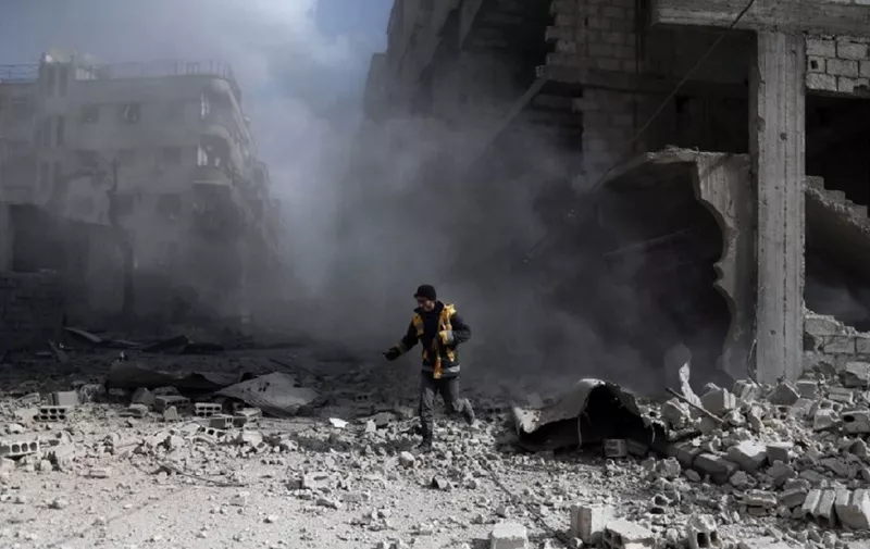 A civil Defence volunteer, known as the White Helmets, checks the site of a regime air strike in the rebel-held town of Saqba, in the besieged Eastern Ghouta region on the outskirts of the capital Damascus, on February 23, 2018.
Syrian regime air strikes and artillery fire hit the rebel-held enclave of Eastern Ghouta for a sixth straight day killing 32 civilians, as the world struggled to reach a deal to stop the carnage. / AFP PHOTO / ABDULMONAM EASSA