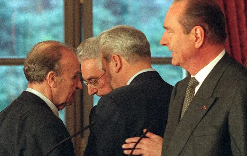 (LtoR) Bosnian President Allja Izetbegovic, Croatian President Franjo Tudjman and Serbian president Slobodan Milosevic huddle in discussion as French President Jacques Chirac (R)  finishes his introduction statement for the signing of peace accord on Bosnia 14 December 1995 at the Elysee Palace in Paris.
