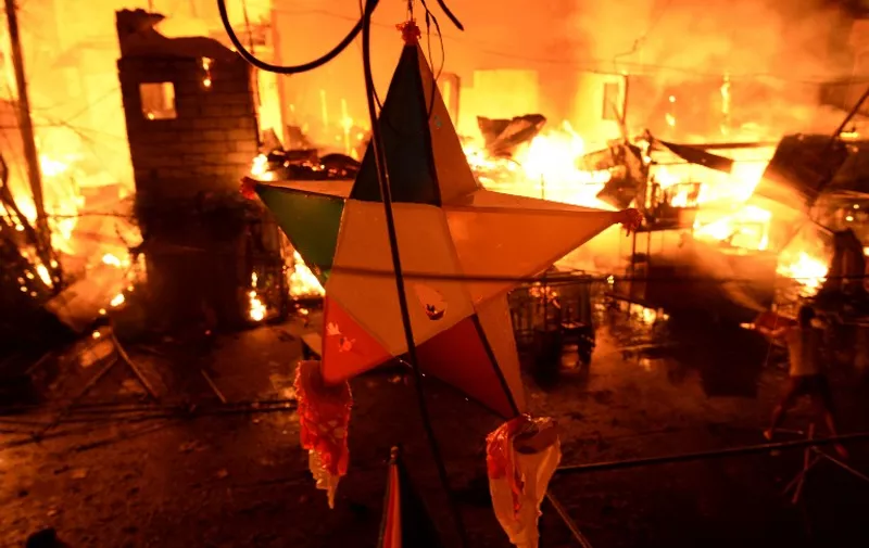 A Christmas decoration is pictured as a huge fire rages through a slum area in Manila on January 1, 2016. Nearly 300 homes were destroyed in the early New Year's Day fire, according to local media reports.    AFP PHOTO / NOEL CELIS / AFP / NOEL CELIS