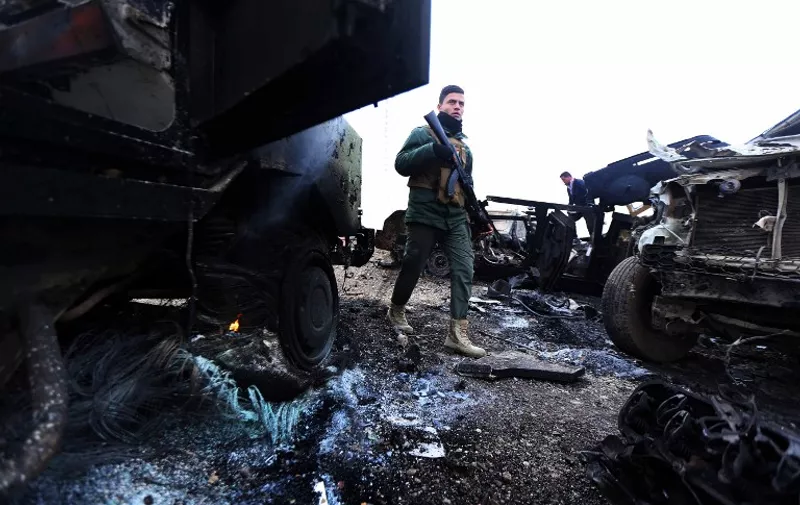 A Peshmerga fighter walks between burning vehicles following a suicide attack carried out by the Islamic State group in Kesarej village, south of to Zummar city, in the northern Iraqi Governorate of Nineveh, near the border with Syria on December 18, 2014. Kurdish forces backed up by US-led warplanes have recaptured a large area in Iraq near the Syrian border in an offensive this week against Islamic State jihadists, a US commander said. AFP PHOTO / SAFIN HAMED / AFP / SAFIN HAMED