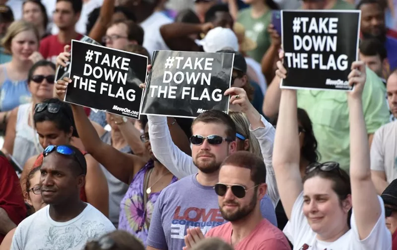 Hundreds of people gather for a protest rally against the Confederate flag in Columbia, South Carolina on June 20, 2015. The racially divisive Confederate battle flag flew at full-mast despite others flying at half-staff in South Carolina after the killing of nine black people in an historic African-American church in Charleston on June 17. Dylann Roof, the 21-year-old white male suspected of carrying out the Emanuel African Episcopal Methodist Church bloodbath, was one of many southern Americans who identified with the 13-star saltire in red, white and blue.      AFP PHOTO/MLADEN ANTONOV