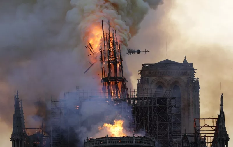 The steeple collapses as smoke and flames engulf the Notre-Dame Cathedral in Paris on April 15, 2019. - A huge fire swept through the roof of the famed Notre-Dame Cathedral in central Paris on April 15, 2019, sending flames and huge clouds of grey smoke billowing into the sky. The flames and smoke plumed from the spire and roof of the gothic cathedral, visited by millions of people a year. A spokesman for the cathedral told AFP that the wooden structure supporting the roof was being gutted by the blaze. (Photo by Geoffroy VAN DER HASSELT / AFP)