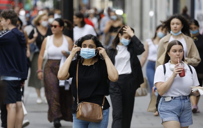 A shopper adjusts her face mask on Oxford Street om London on July 24, 2020, after wearing facemasks in shops and supermarkets became compulsory in England as a measure to combat the spread of the novel coronavirus. (Photo by Tolga AKMEN / AFP)