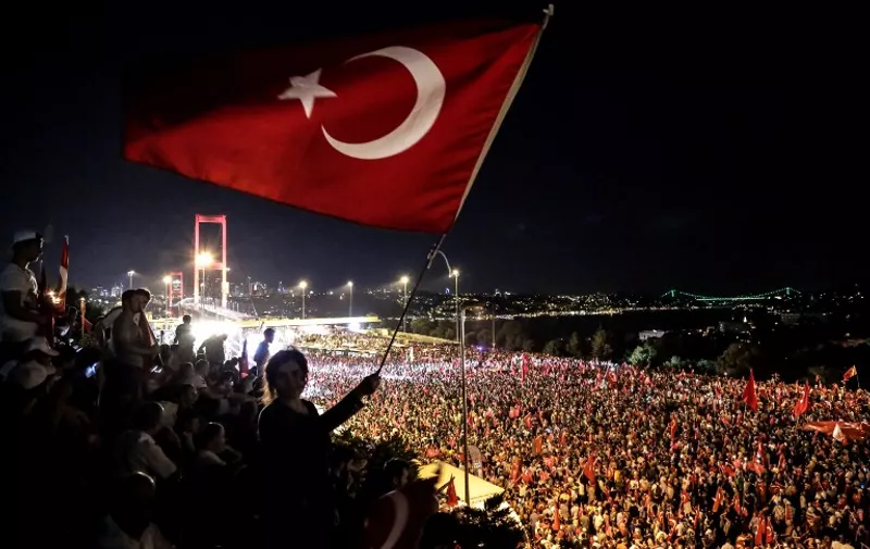 Pro Erdogan supporters wave a Turkish national flag during a rally at Bosphorus bridge in Istanbul on July 21, 2016. 
Thousands of Turkish government supporters on Thursday streamed across one of the two bridges spanning the Bosphorus in Istanbul to protest against the coup that sought to unseat President Recep Tayyip Erdogan one week ago. The Bosphorus Bridge between the Asian and European sides of Istanbul was one of the key battlegrounds in Friday night's coup attempt, as rebel soldiers descended in tanks to block it to traffic and then engaged in battles with opponents. / AFP PHOTO / UMIT TURHAN COSKUN