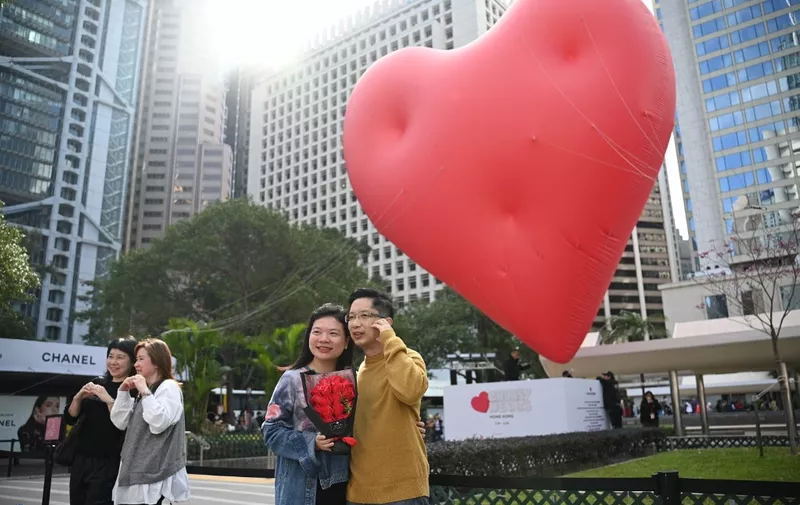 A couple pose for photos in front of a giant heart on Valentine's Day in Hong Kong on February 14, 2024. (Photo by Peter PARKS / AFP)